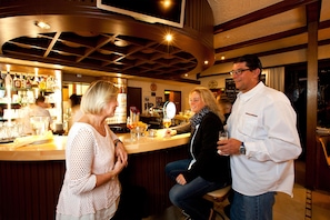 A bar area with a counter, stools, and a variety of bottles and glasses. - Best Western Hotel St. Michael (Morbach)