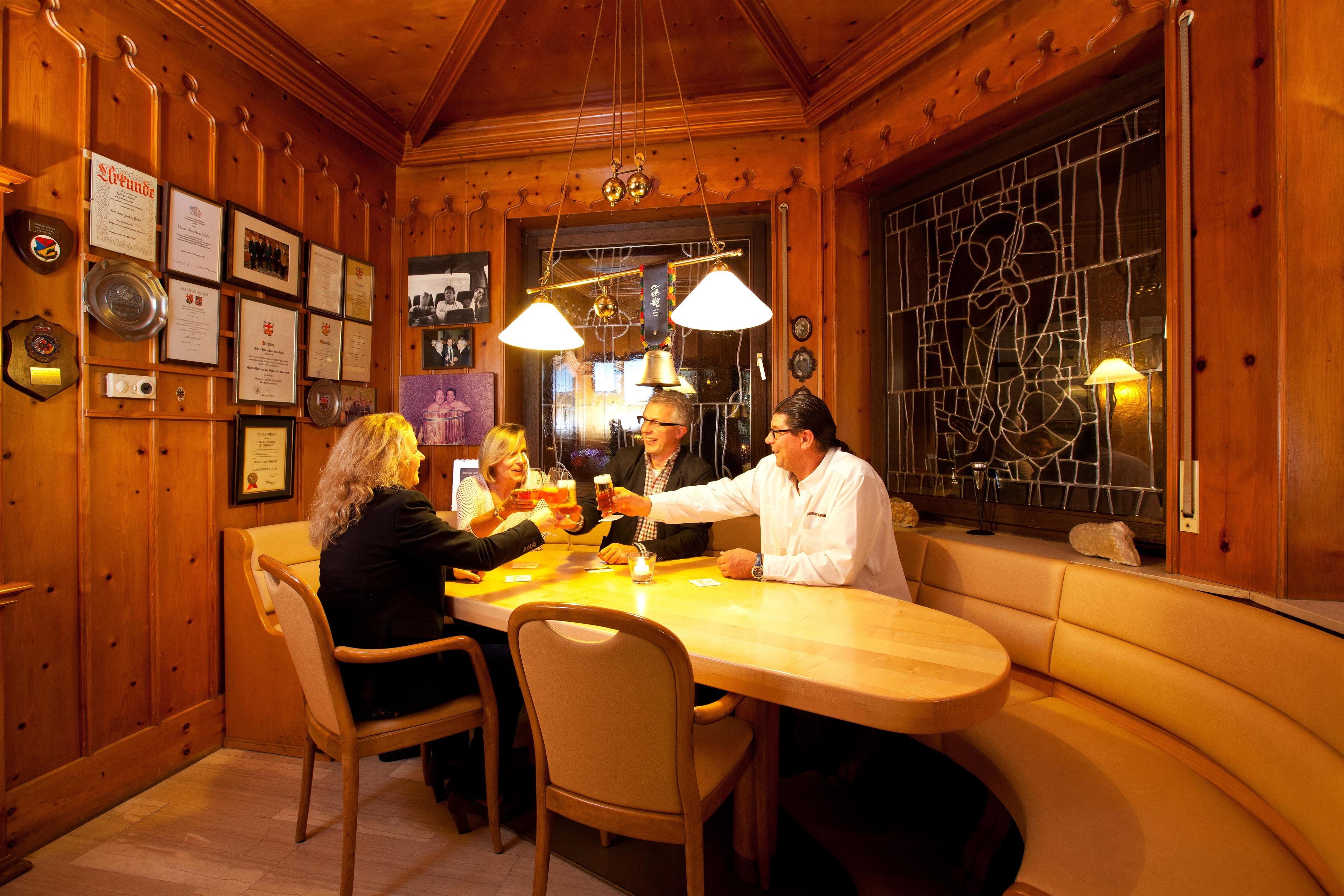 Un interior de madera con una mesa de comedor, sillas, diplomas enmarcados y un ventanal de vidrio emplomado.