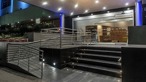 A modern hotel entrance with a glass facade, a staircase with metal railings, and a reception desk. - Holiday Inn Express Mexico - Toreo by IHG (Naucalpan)