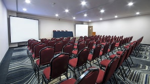 A conference room with rows of red chairs, a projector screen, and a carpeted floor. - Holiday Inn Express Mexico - Toreo by IHG (Naucalpan)