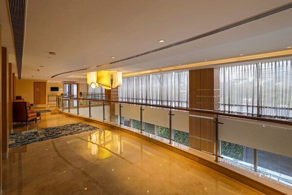 Un hall d’entrée spacieux, doté d’un sol poli, d’une balustrade incurvée et de grandes fenêtres ornées de rideaux légers.