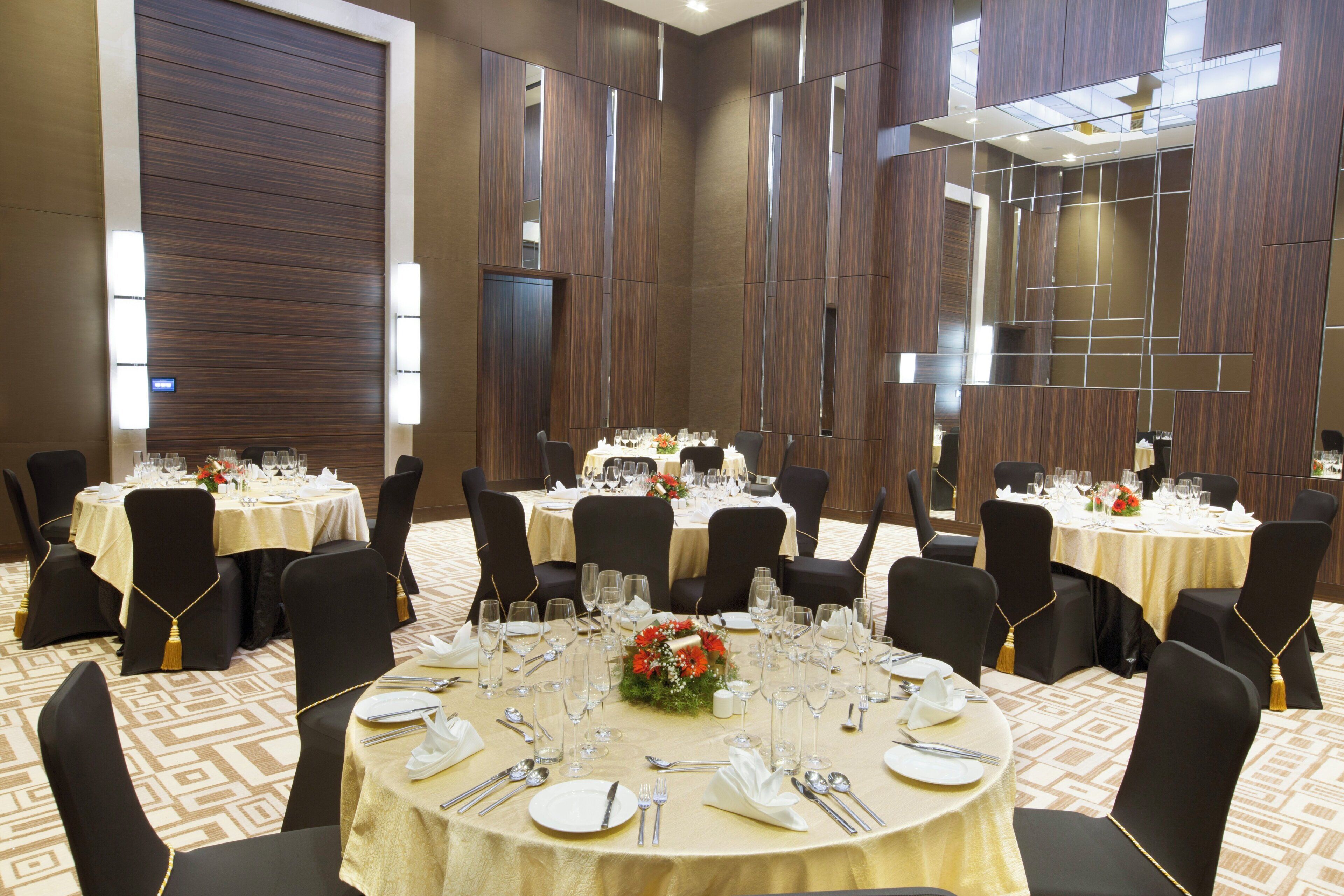 A conference room with multiple round tables, black chairs, and a carpeted floor.