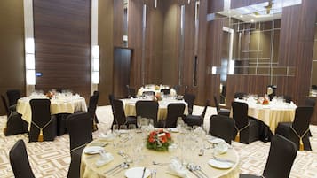 A conference room with multiple round tables, black chairs, and a carpeted floor.