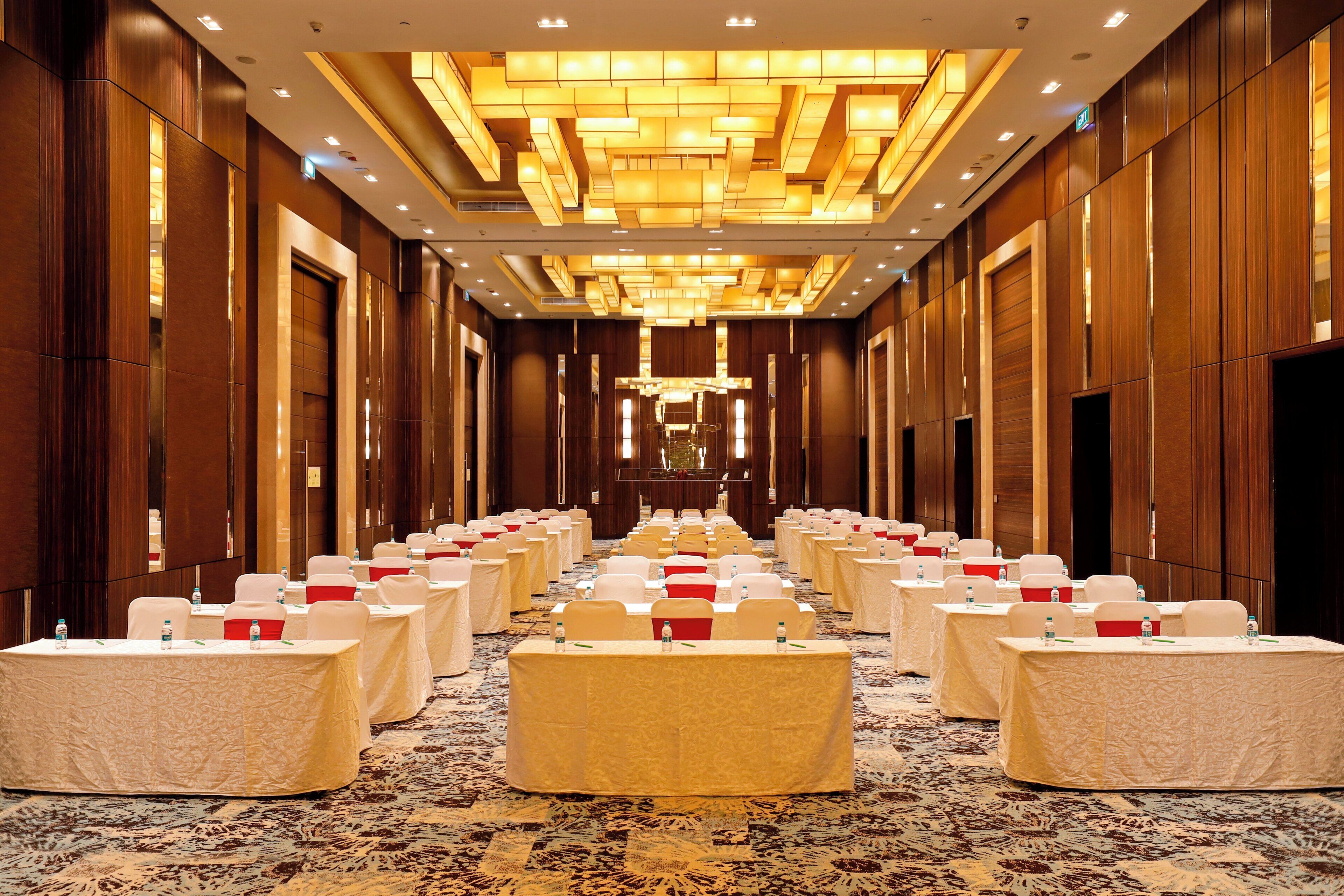 Une salle de conférence d’hôtel avec des rangées de tables, des chaises et un sol recouvert de moquette.