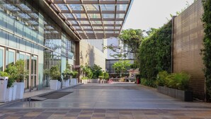 Un edificio moderno con fachada de vidrio, un paseo techado y plantas en macetas.