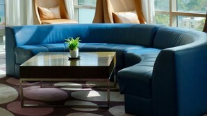 Una sala de estar moderna con un sofá seccional azul, dos sillones de cuero, una mesa de centro y dos lámparas colgantes de malla negra.