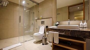 Une salle de bain moderne avec une douche à l’italienne en verre, des toilettes, un lavabo doté d’un plan de travail en marbre et un miroir au-dessus du lavabo.