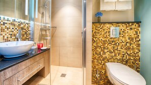 A modern bathroom with a glass-enclosed shower, a large white sink, and a mosaic-tiled wall. - Leonardo Hotel Munich City South (Munich)