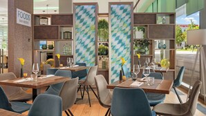 A restaurant interior with multiple tables, chairs, and a sign indicating a bar and bistro. - Leonardo Hotel Munich City South (Munich)