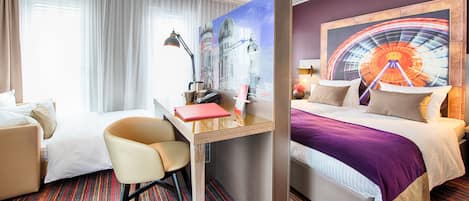Habitación de hotel con cama, escritorio y silla, ventana con cortinas y un cuadro grande en la pared.