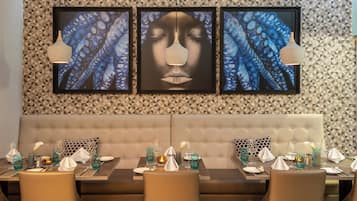 A dining area with a long table set for a meal, a cushioned bench, and framed artwork on the wall.