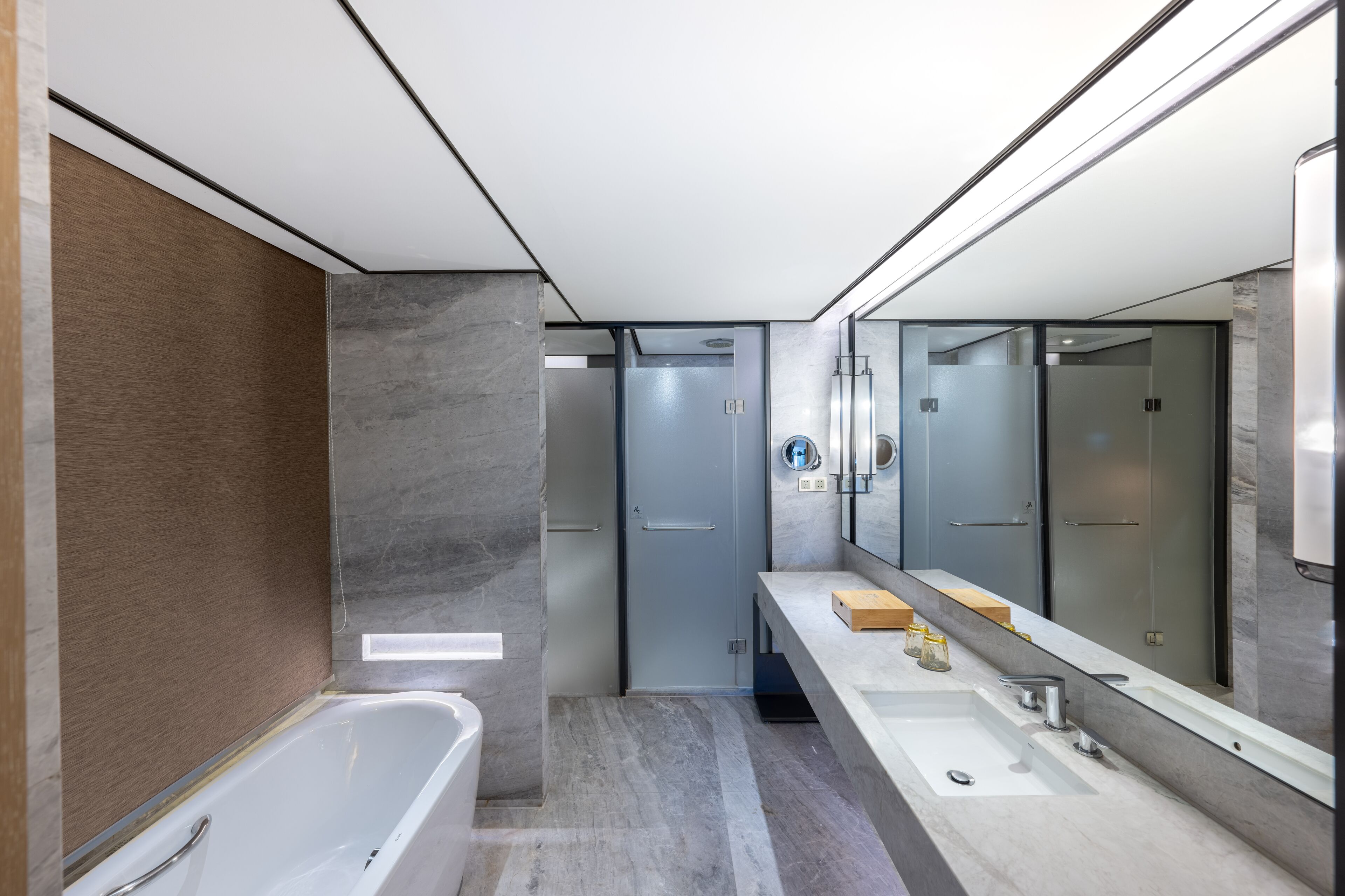 Un baño moderno con bañera, dos lavamanos, un espejo grande y una puerta que da a otra habitación.