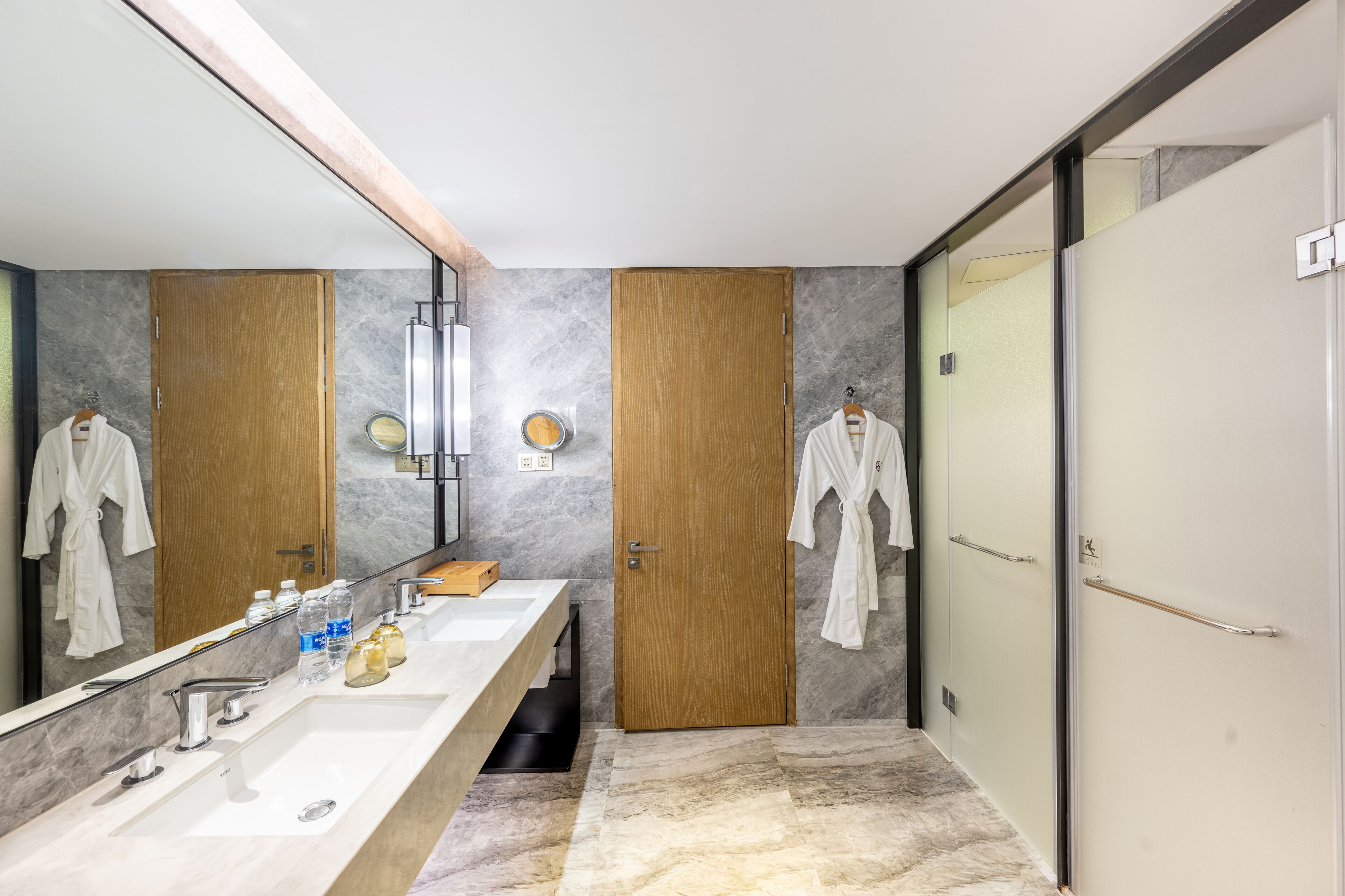 Un baño moderno con un espejo grande, un tocador amplio y dos puertas de madera.