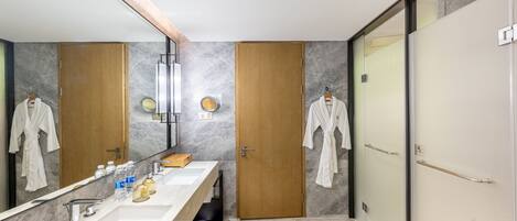 Un baño moderno con un espejo grande, un tocador amplio y dos puertas de madera.