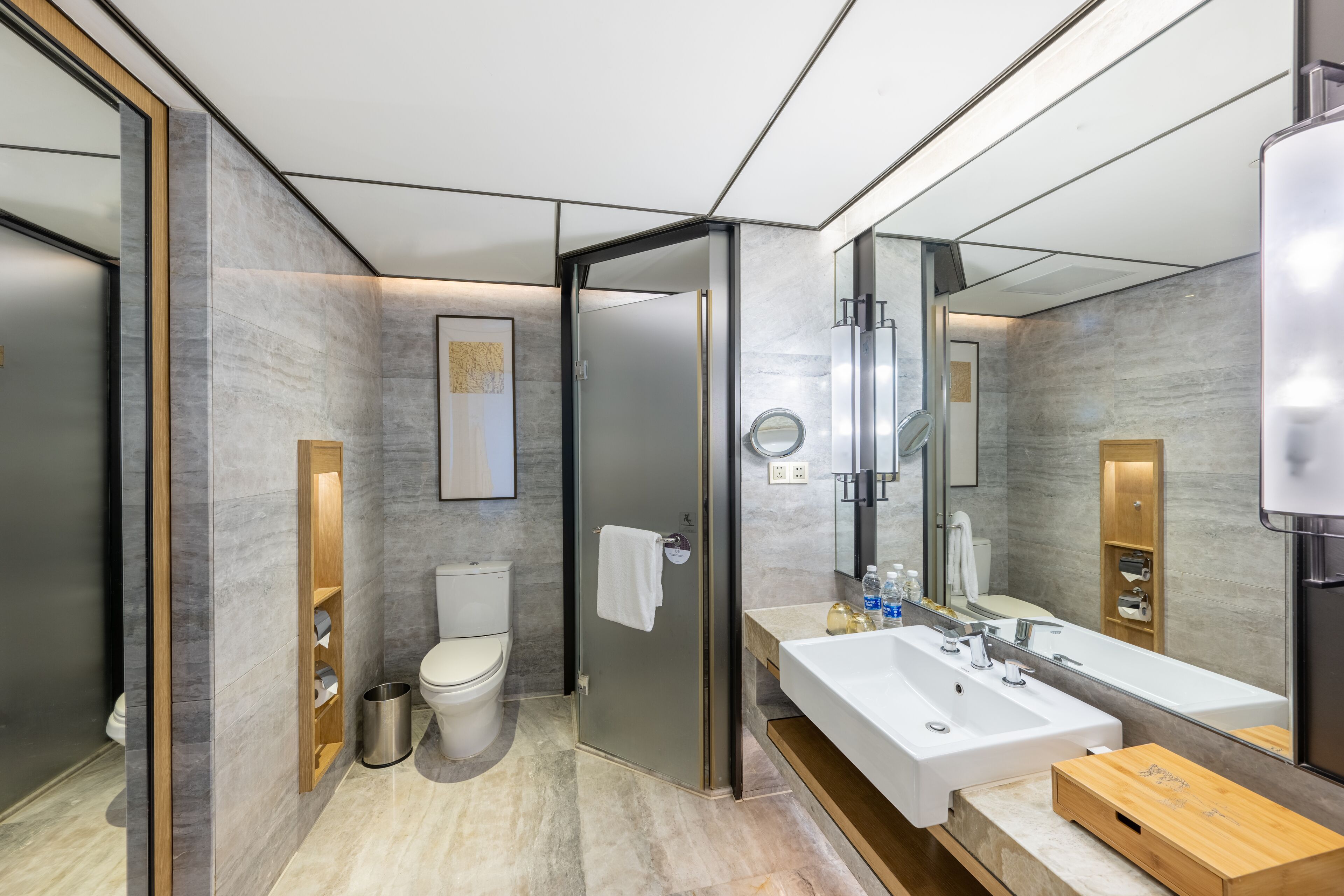 Un baño moderno con un espejo grande, un lavabo blanco y un inodoro.