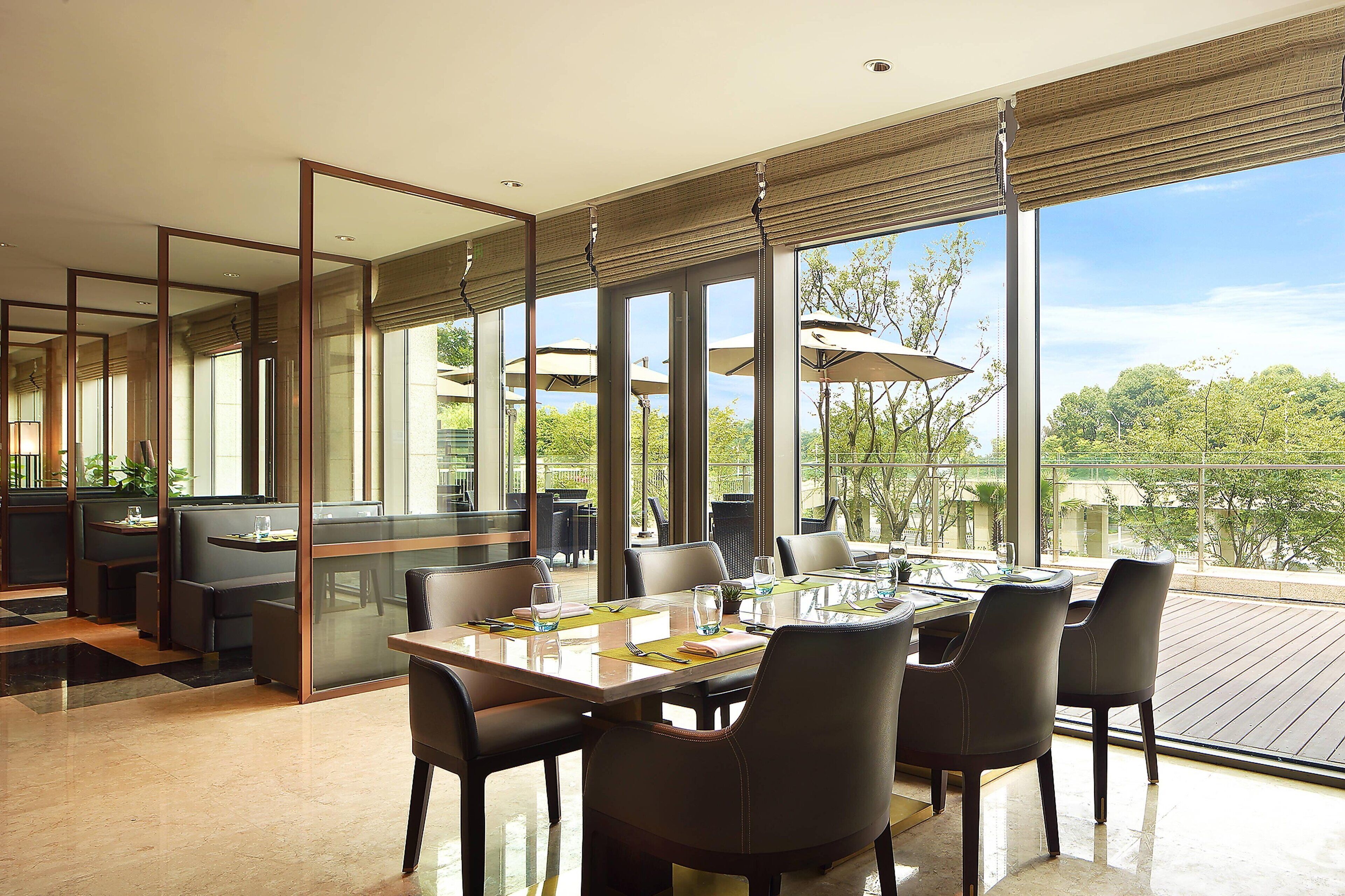 A modern dining area with a large table, chairs, and a view of the outdoors.