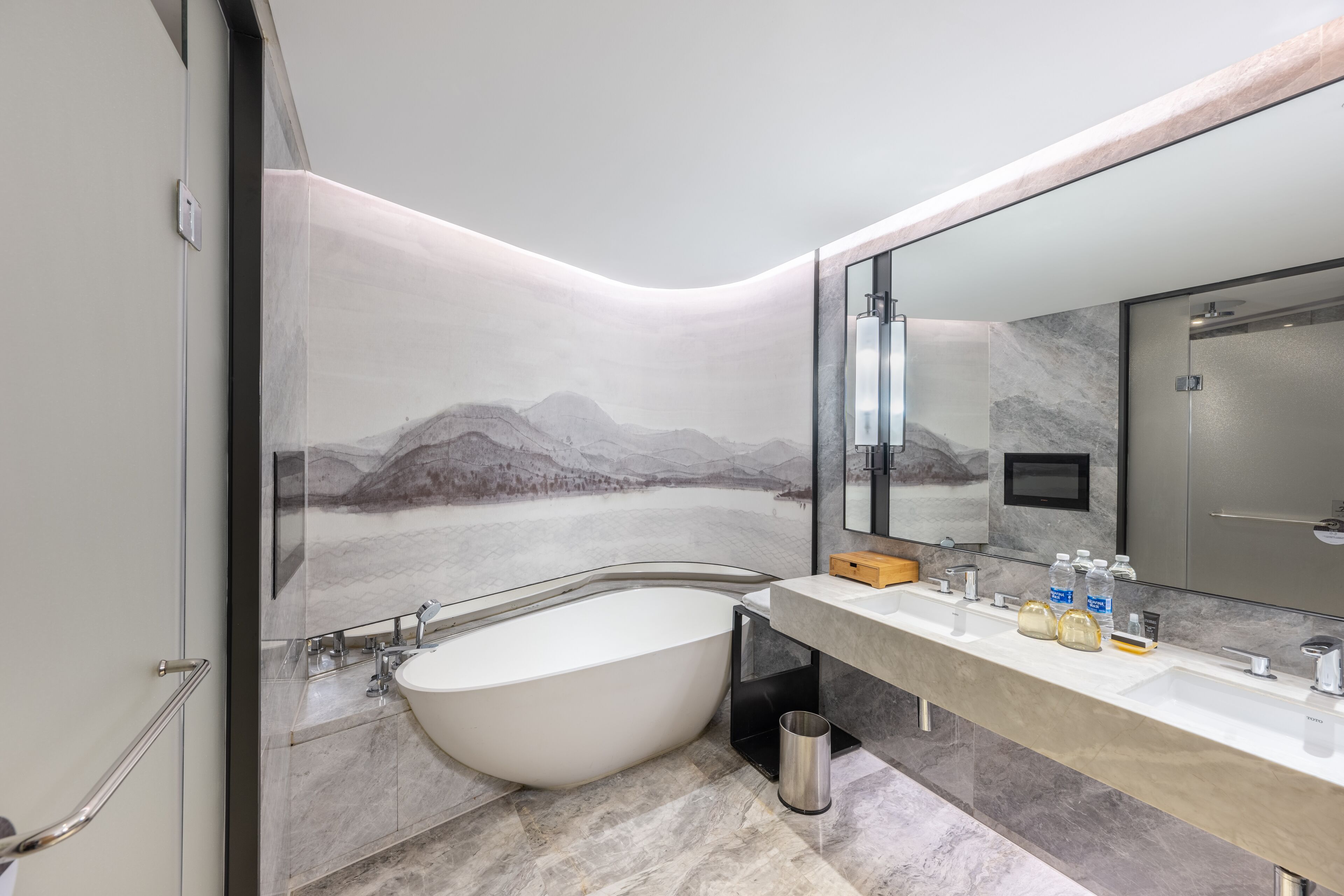 A modern bathroom with a freestanding bathtub, a large mirror, and a vanity with multiple sinks.