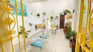 A bright, open-plan living area with a dining table and chairs, surrounded by potted plants and a yellow decorative railing. - Casa Canario La Americana (Guadalajara)