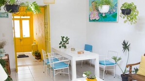 A bright, spacious room with a white table, blue chairs, and hanging plants. - Casa Canario La Americana (Guadalajara)
