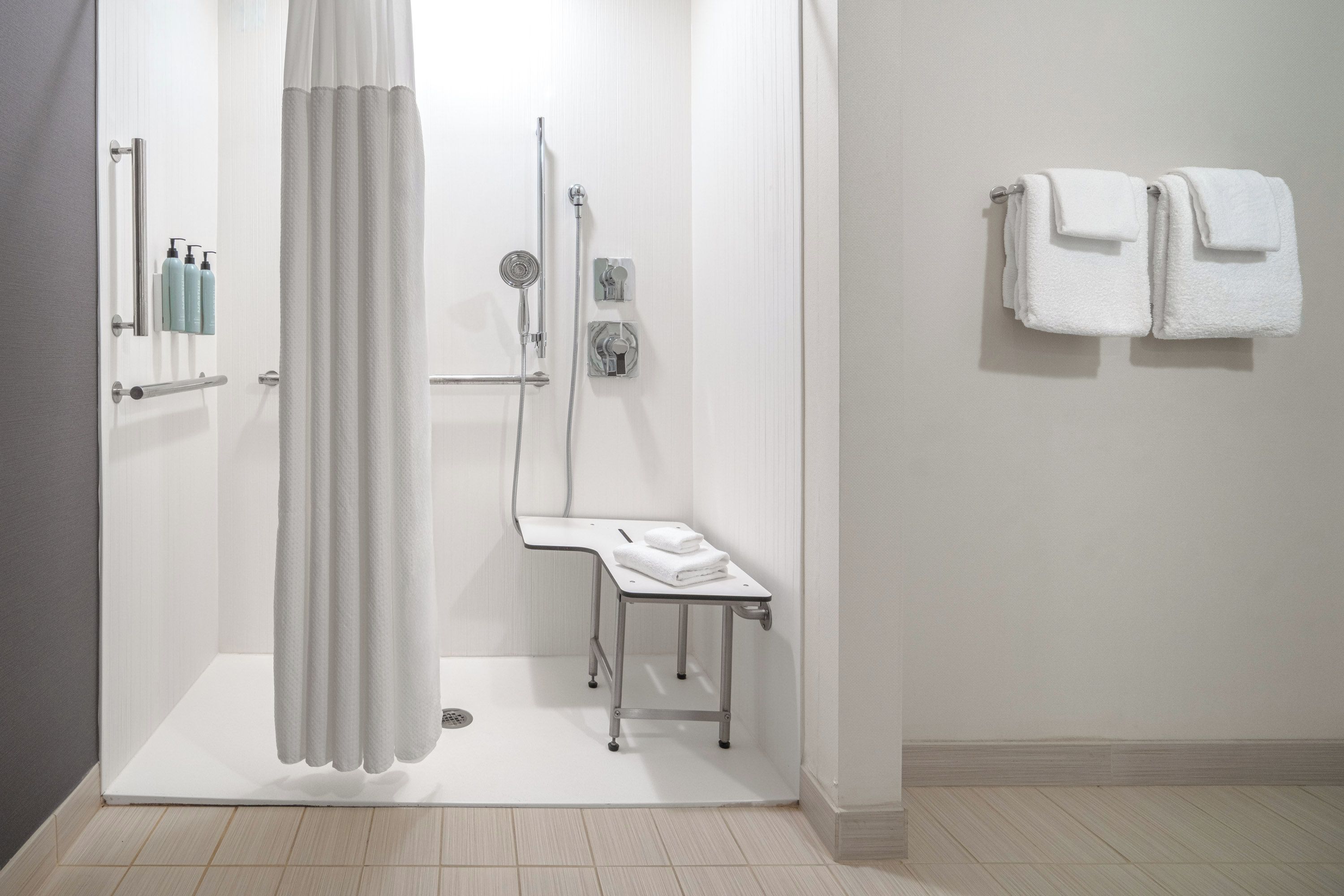 A modern bathroom with a shower, a towel rack, and a small table.