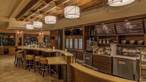 A bar area with stools, a counter, and a menu board. - Courtyard by Marriott Pigeon Forge (Pigeon Forge)