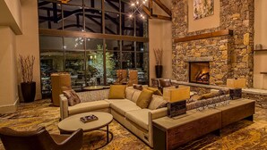 A spacious living area with a large window, a stone fireplace, and modern furniture. - Courtyard by Marriott Pigeon Forge (Pigeon Forge)