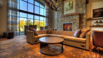 A spacious living room with a stone fireplace, large windows, and a cozy seating area.