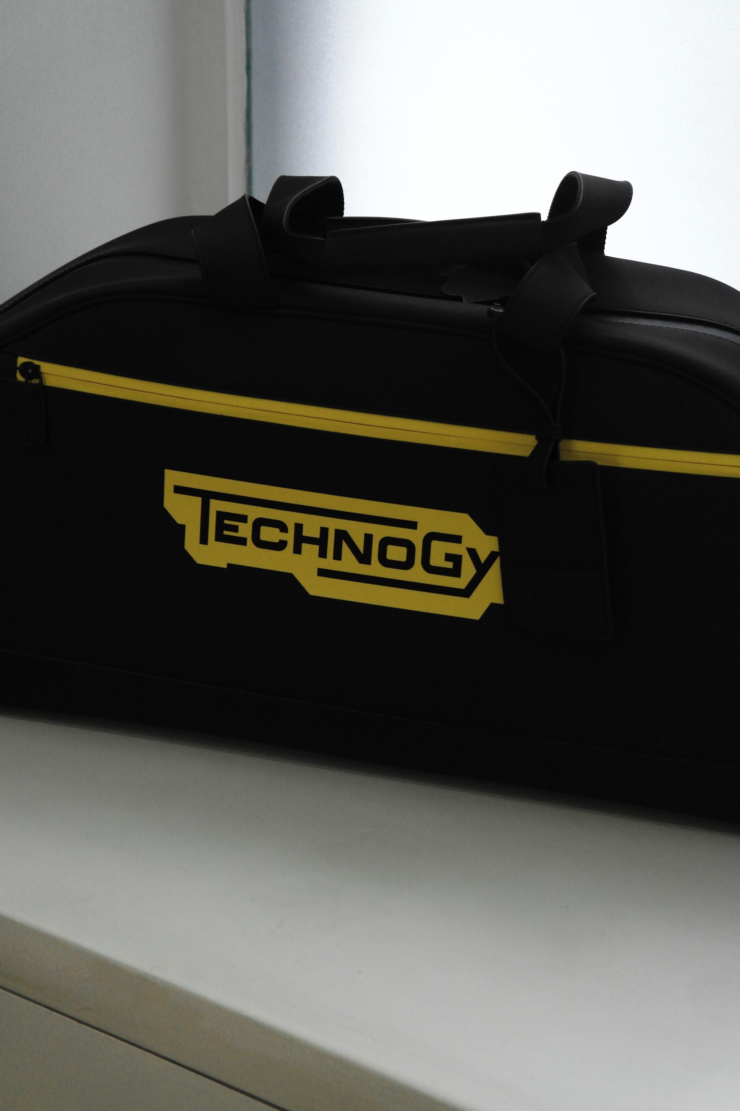 En sort rejsetaske med et gult "TECHNOLOGY" logo.