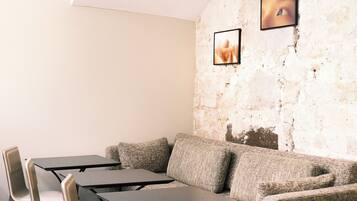 Un interior moderno con suelo de piedra, un sofá, una mesa y sillas.