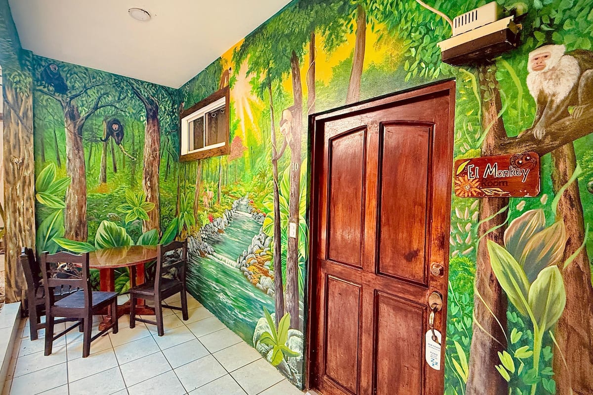 A room with a mural of a forest scene, a wooden door, and a sign reading "El Monkey".
