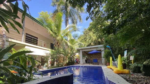 A swimming pool with tiled edges, surrounded by lush greenery and a covered seating area. - Hotel La Posada and Jungle (Quepos)