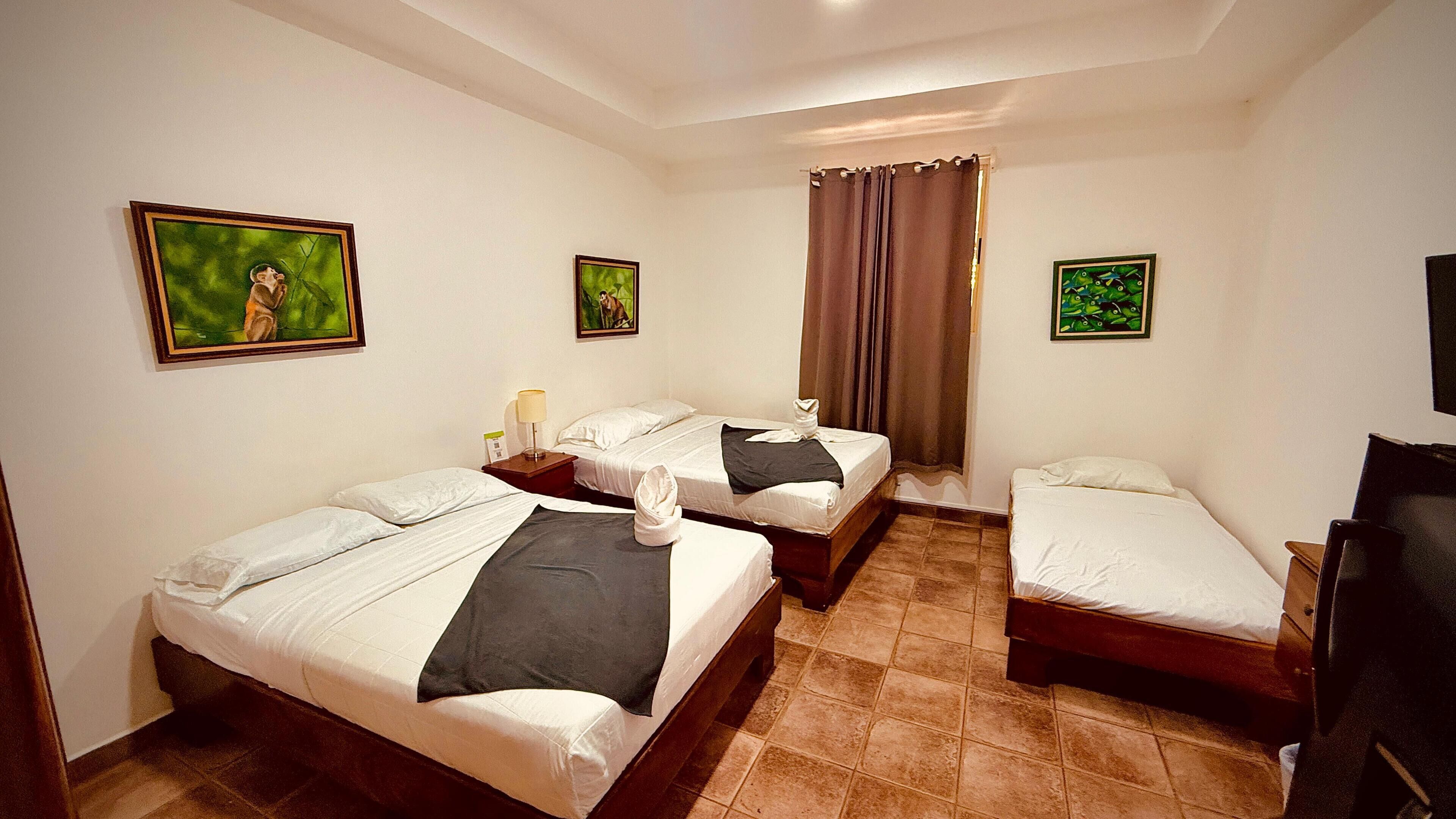A hotel room with two single beds, a TV, and artwork on the walls.