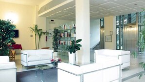 Un vestíbulo moderno con sofás blancos, una mesa de centro de vidrio y una estantería.