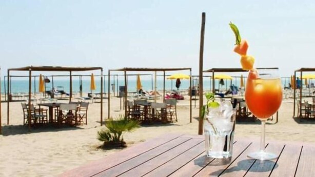 Un restaurante frente a la playa con terraza y sombrillas.