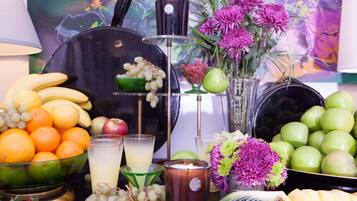 A table with fruits, a candle, and a vase of flowers.