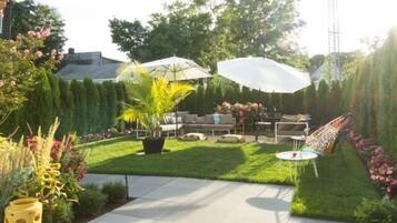 A backyard with a lawn, patio furniture, and potted plants.