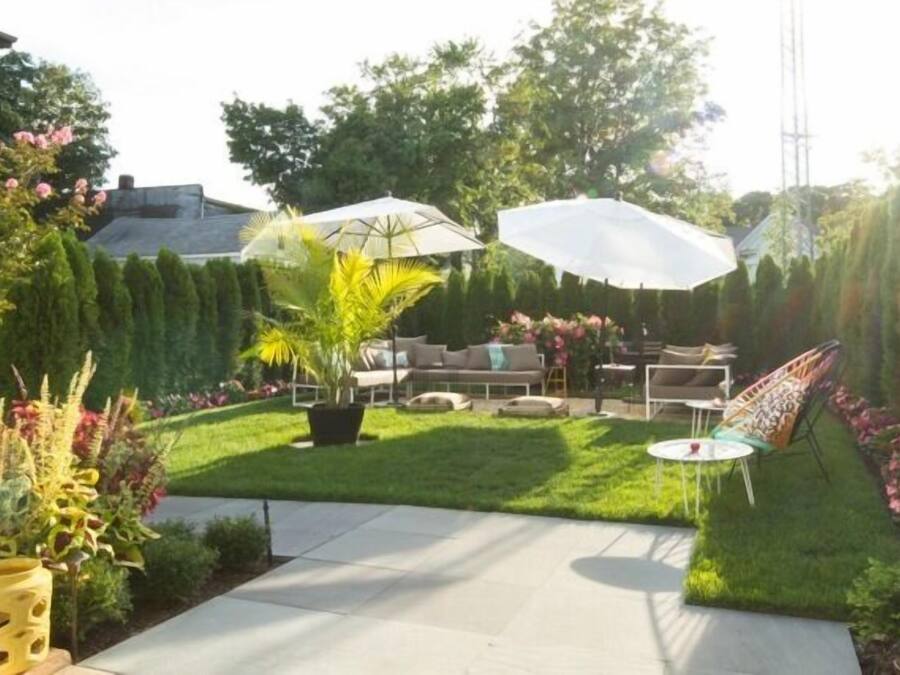 A backyard with a lawn, patio furniture, and potted plants.