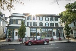 A hotel with a modern facade, large windows, and a parked car in front.