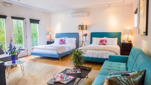 A modern bedroom with two beds, a sofa, a coffee table, and a potted plant. - Zey Hotel (Greenport)