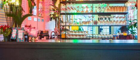 Un espace bar avec des tabourets, une étagère avec des verres et des plantes décoratives.
