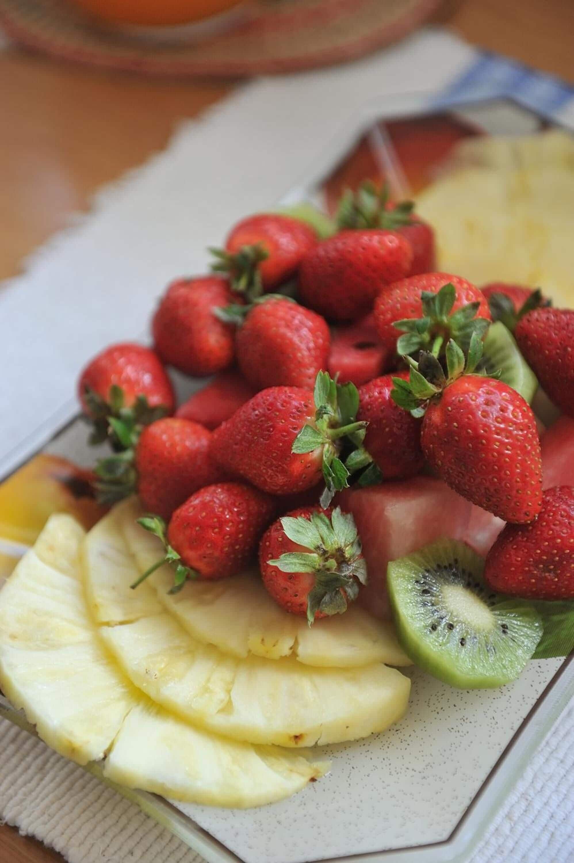 A plate of sliced pineapple, watermelon, and strawberries.