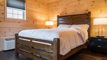 A wooden-paneled bedroom with a bed, bedside lamps, and a window.