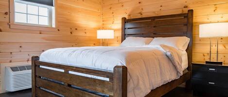 Een slaapkamer met houten lambrisering, een bed, bedlampjes en een raam.