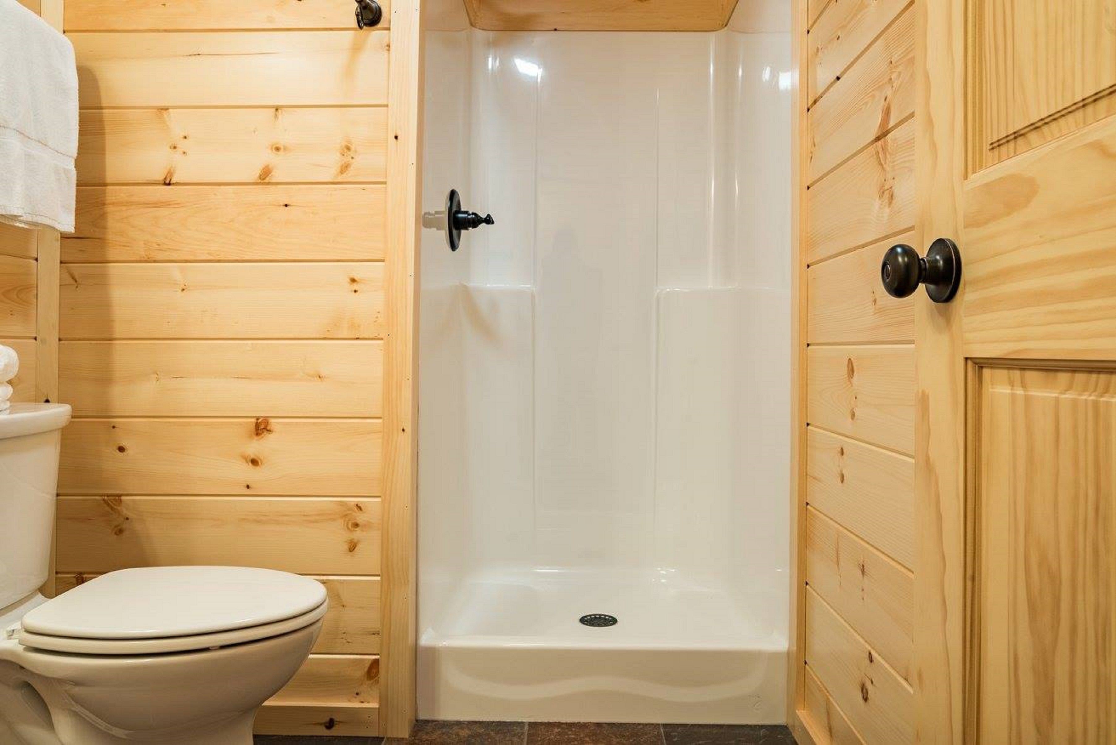 Un baño con paneles de madera, un inodoro, una ducha y un armario.