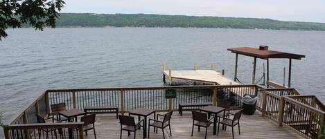 A wooden deck with tables and chairs overlooking a lake.