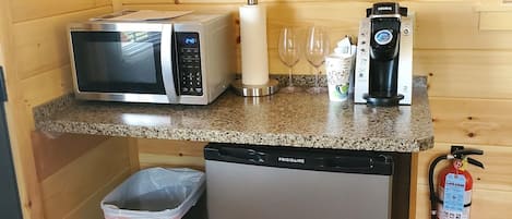 Una cocina compacta equipada con microondas, cafetera y un refrigerador pequeño.