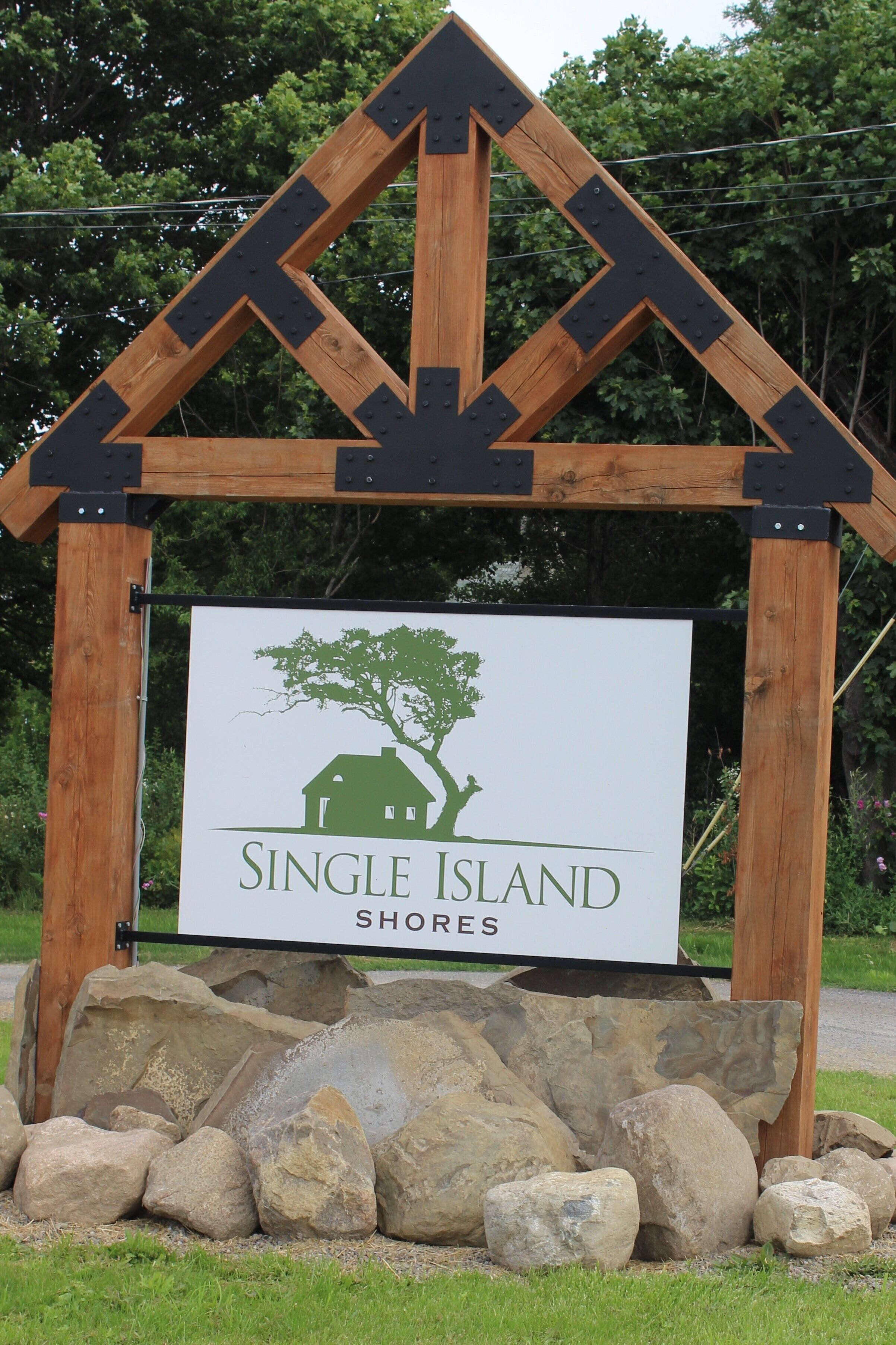 A wooden sign with a house and tree logo, labeled "Single Island Shores".