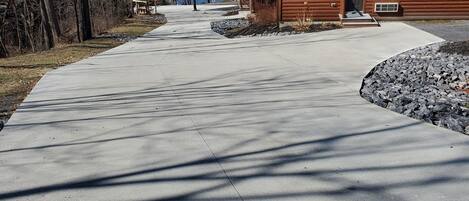 Una cabaña de madera con un camino de concreto que lleva a un muelle junto a un lago.