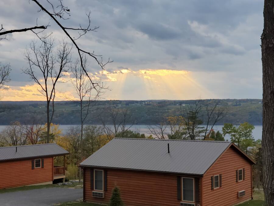 A cabin with a metal roof, a porch, and a view of a lake and forest.