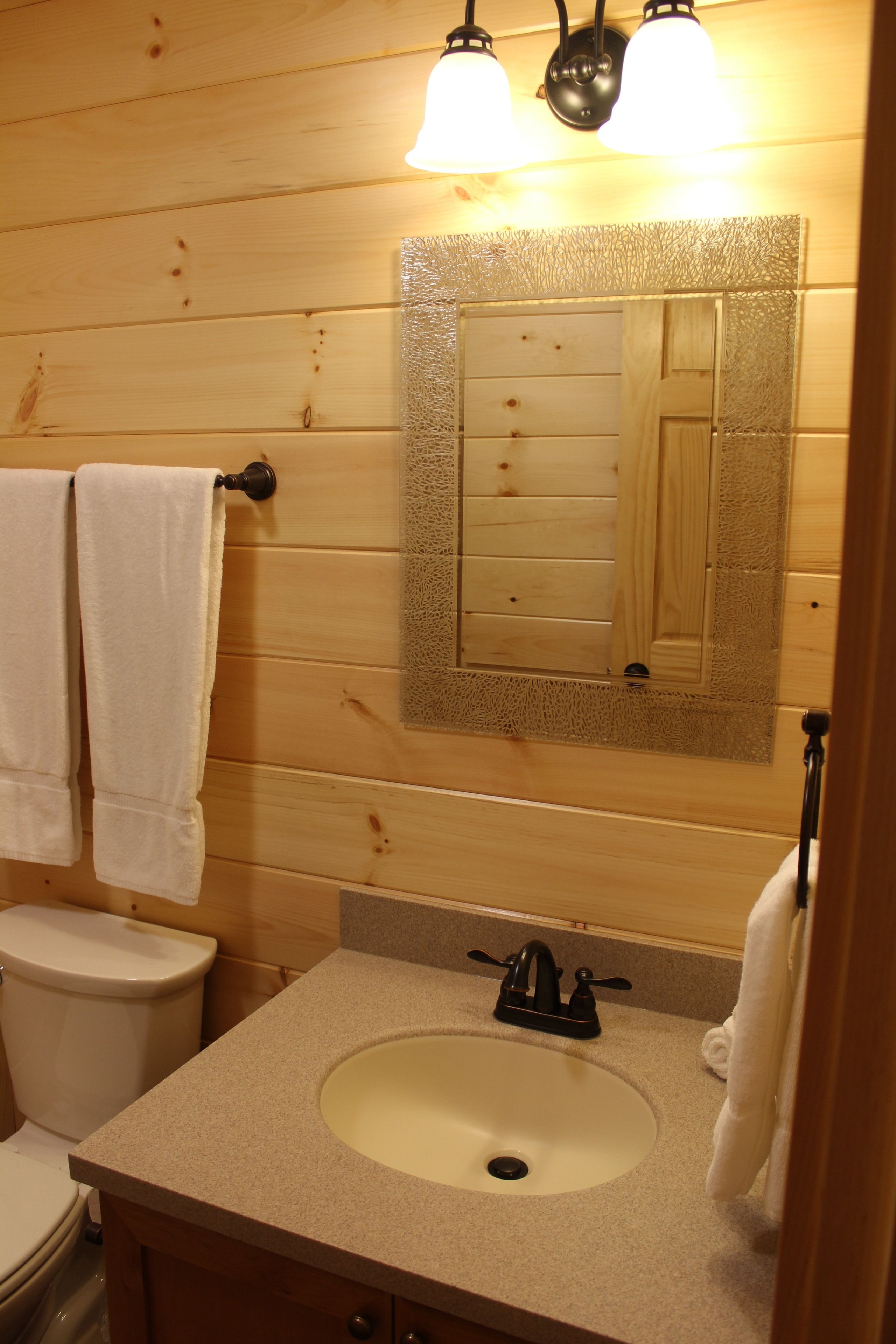 A bathroom with wooden walls, a white sink, and two towels hanging on hooks.